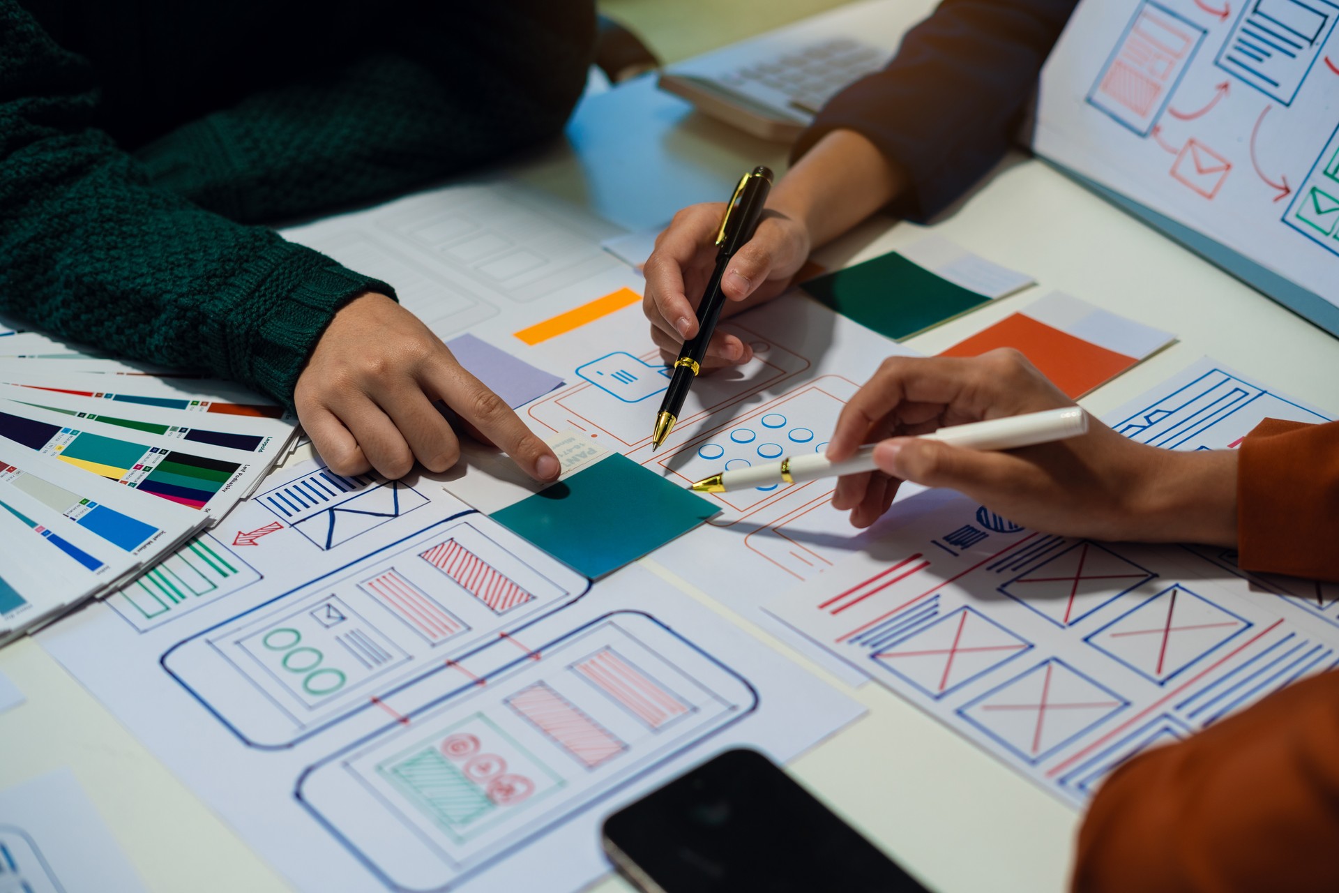 UX developer and ui designer brainstorming about mobile app interface wireframe design with customer breif and color code at office.